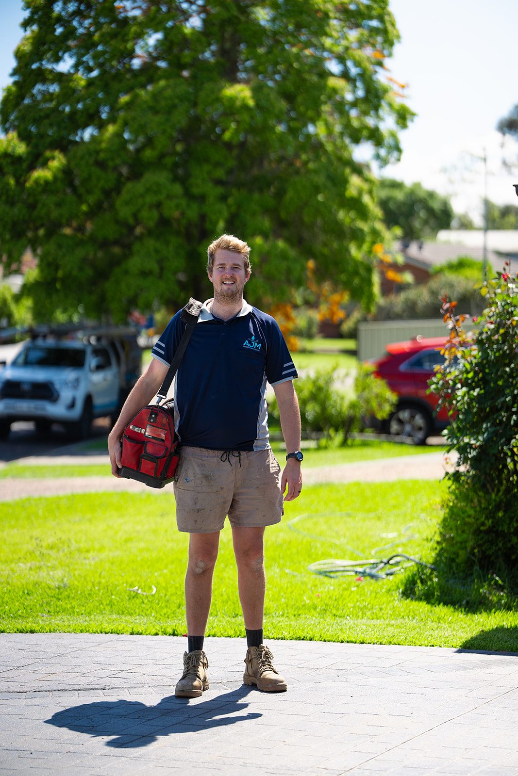 Aaron from AJM Plumbing Solutions with his tool bag on a front lawn
